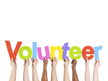 hands raised holding colourful letters saying volunteer