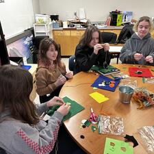Four female students at a table doing a craft